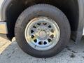 A close-up of a chrome wheel from a 2022 GMC Sierra 1500 featuring a detailed design and a rugged tire with prominent tread patterns