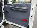 The image shows the interior door panel of a 2001 Ford F-350 featuring a gray handle a speaker grille and a red light at the bottom