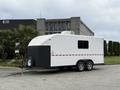A white 2025 Shuttle Office trailer with a black trim and single window on the side, attached to a trailer hitch with wheels visible