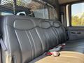 A spacious black leather bench seat in a 2005 GMC C7500 Topkick with seatbelts and a protective mesh barrier behind it