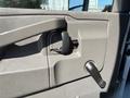 The interior door panel of a 2020 Chevrolet Express featuring a door handle a manual window crank and storage space