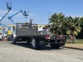 A 2004 Ford F-750 truck with a flatbed and a wooden stake body parked in a lot