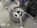 A silver wheel with a tire secured to the floor using black straps in a vehicle interior