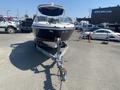 A 2013 Larson 238 boat is positioned on a trailer with the bow facing forward featuring a sleek design and a covered cockpit