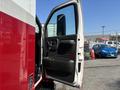 A white and red 2007 GMC C4500 TopKick with the driver's door open, showing the interior door panel and seat