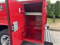 A red Chevrolet Silverado 3500HD truck bed storage compartment with an open door revealing empty shelves and interior space