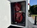 A closed storage compartment revealing two red hose reels mounted on a wall with connected hoses and a motor underneath