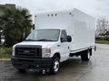 A 2024 Ford E-450 box truck with a white cargo box and black grille parked on a wet surface