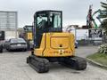 A 2017 John Deere 50G compact excavator with a yellow and black exterior facing away from the viewer showcasing its tracks and cabin design