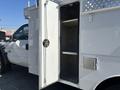 A 2011 Ford F-550 with an open compartment door showing a spacious interior storage area with metal walls and shelves