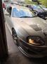 A 1997 Toyota Supra in silver color with a sleek design and modified body kit features round headlights and prominent hood vents