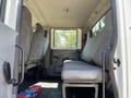 Interior view of a 2011 International 4300 cab with a single bench seat and seatbelts visible along with a floor-mounted gear shifter and minimal equipment on the floor
