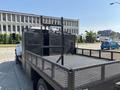 A 2005 GMC C7500 Topkick truck with a flatbed and a black metal railing on the side viewed from the rear angle