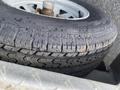 A close-up of a black tire with worn tread patterns mounted on a metal wheel hub of a 2014 Express 8 Foot Trailer