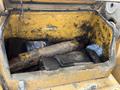 Open storage compartment of a 2018 John Deere 350 containing tools and a blue cloth with various parts visible inside