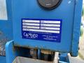A blue inspection sticker on a Genie TZ-34/20 lift displaying the make, model, serial number, unit number, inspection date, and company contact information