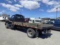 A 1996 GMC Top Kick flatbed truck with a black and orange exterior and a wooden flatbed visible in the foreground