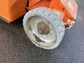 A close-up of a wheel from a 2012 JLG E400AJFN with a gray tire and a rusty metal rim showing signs of wear and dirt