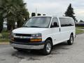 A white 2004 Chevrolet Express van with a black grille and chrome bumper parked on a paved surface with palm trees visible in the background