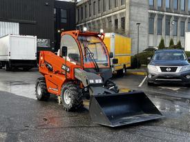 A 2023 JLG 10054 compact loader with a red and black body and a front bucket attached stands ready for operation