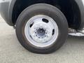 A close-up of a silver wheel featuring multiple lug nuts and a tire with a black tread on a 2011 Dodge Ram 5500