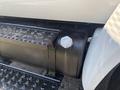 A close-up of a fuel tank on a 2004 Ford F-750 with a round cap and a textured step plate below it