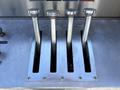 Four shiny metal levers positioned vertically in a row on a silver panel with slots for each lever below them