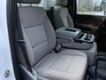 A gray cloth front seat of a 2017 GMC Sierra 3500HD featuring an armrest with cup holders and a console between two seats