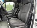 Interior view of a 2016 Mercedes-Benz Sprinter showing two gray fabric front seats with a minimalist design and seatbelt attachments