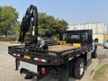 A black 2009 Ford F-450 Super Duty flatbed truck with a crane attachment on the side and wooden planks on the flatbed