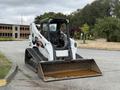 A 2017 Bobcat T740 skid-steer loader with a front bucket and rubber tracks positioned on a paved surface