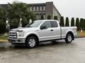 A 2015 Ford F-150 in silver with a pickup truck design featuring four doors and four-wheel drive