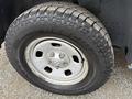 Close-up of a 2016 RAM 1500 tire with a rugged tread design and a silver alloy wheel displaying five lug nut openings