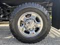 A shiny chrome wheel of a 2013 RAM 2500 with a rugged all-terrain tire showcasing detailed tread patterns and prominent wheel bolts