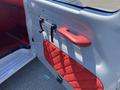 Interior door panel of a 1962 Ford 2WHDR featuring a red quilted fabric design and a red handle alongside two black door pulls