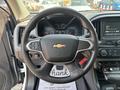 A steering wheel of a 2017 Chevrolet Colorado featuring a silver and black design with the Chevrolet logo in the center and control buttons on the left