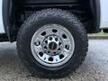 Close-up of a chrome wheel with a large rugged tire featuring an all-terrain tread pattern displaying the GMC logo in the center
