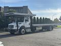 A 2022 Freightliner M2 106 flatbed truck with a large open cargo area and a raised cab designed for transporting heavy loads
