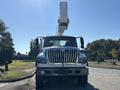 A 2013 International 7500 truck with a large white aerial lift mounted on top facing the viewer