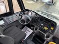 Interior view of a 2022 Freightliner B2 bus showing the driver's seat dashboard controls and gear shifter with a "Thank You" floor mat