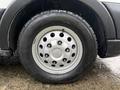 A close-up of a silver wheel with lug nuts and a black winter tire marked with the word WINTER on it