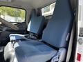 Interior of a 2013 Mitsubishi Fuso FE160 showing two blue fabric front seats with seatbelts and a steering wheel