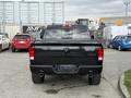 A black 2018 RAM 1500 pickup truck viewed from the rear with dual exhaust pipes and a prominent RAM logo on the tailgate