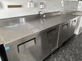 A stainless steel countertop with three storage compartments and a faucet at the edge