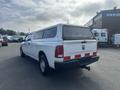 A white 2012 RAM 2500 pickup truck with a cap on the bed and red and white reflective tape on the rear bumper