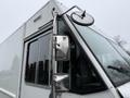 A 2012 Ford Econoline with a prominent side mirror and large windshield showcasing its boxy design and utilitarian features