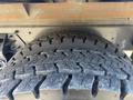 Close-up of a large tire with a deep tread pattern designed for off-road traction mounted on a truck chassis