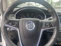 The steering wheel of a 2018 Buick Encore featuring the Buick emblem and various control buttons for audio and cruise settings