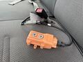 An orange electronic device with two metal connections and a cable lies on the seat of a 2004 Ford F-350 SD