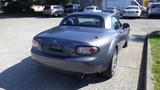 A gray 2007 Mazda Miata parked with a closed hardtop and stylish rear design featuring circular taillights and dual exhaust pipes